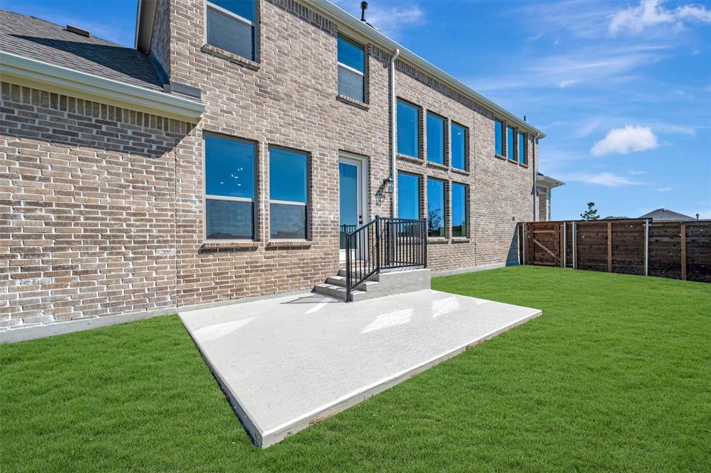 Brick exterior with multiple windows, concrete patio, green lawn, and wood privacy fencing Brick exterior with multiple windows, concrete patio, green lawn, and wood privacy fencing