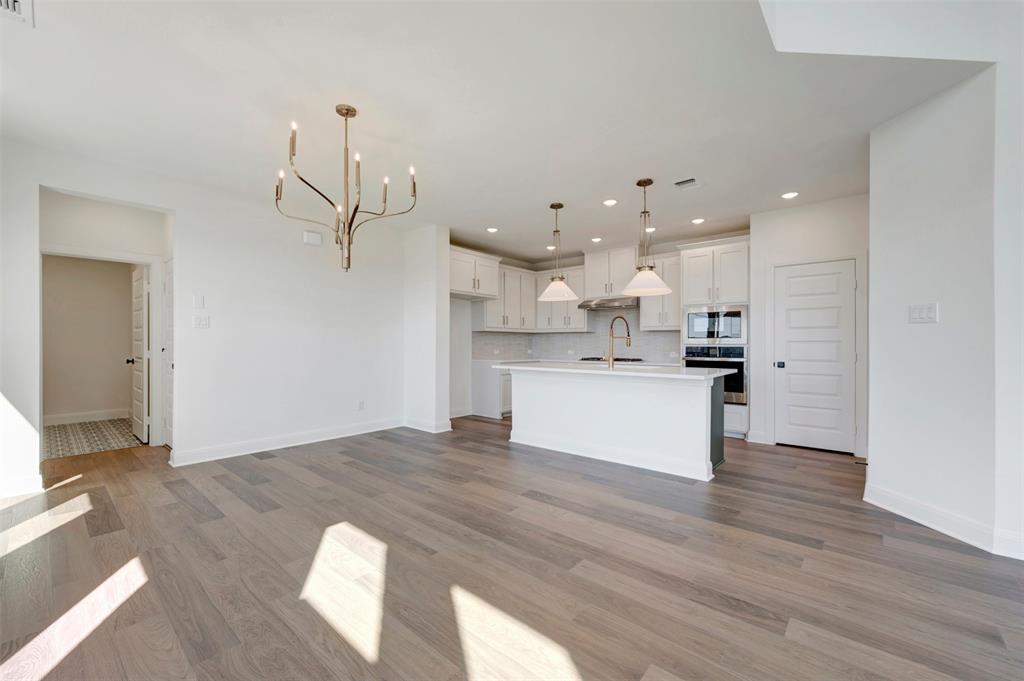 Open-concept living area with wood-finish flooring, a contemporary chandelier, and recessed lighting