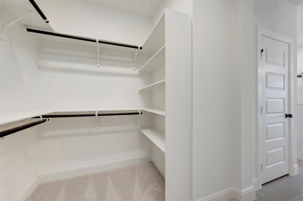 Walk-in closet featuring extensive shelving, multiple hanging rods, and light-toned carpeting