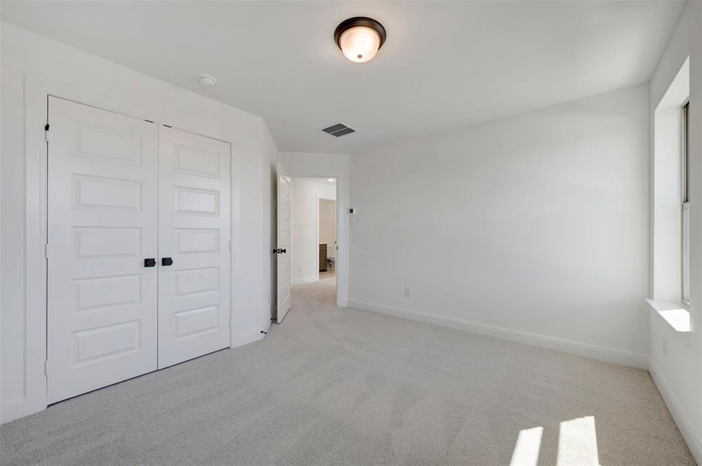 Carpeted flooring, white walls, window with sill, flush mount light fixture, and paneled double doors with dark hardware