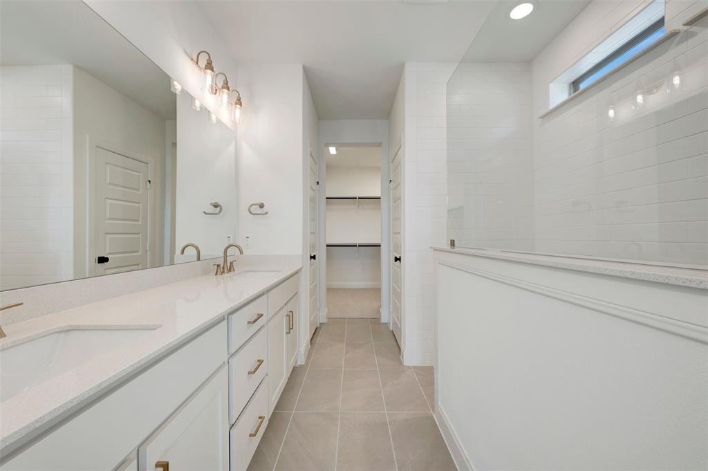 Double vanity with integrated sinks, white cabinetry, and gold-finish hardware Double vanity with integrated sinks, white cabinetry, and gold-finish hardware