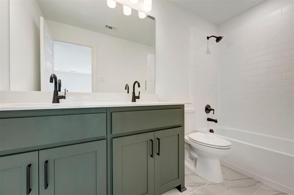 Dual vanity with dark green cabinetry and a light-toned countertop, featuring matte black fixtures