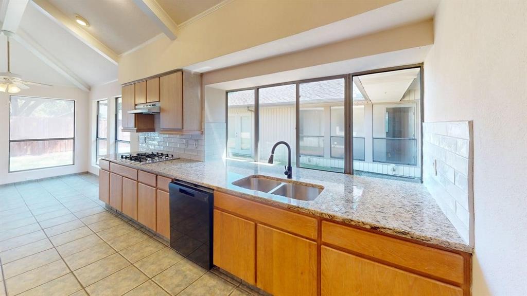 Kitchen featuring granite countertops, wood cabinetry, tile flooring, and a gas cooktop
