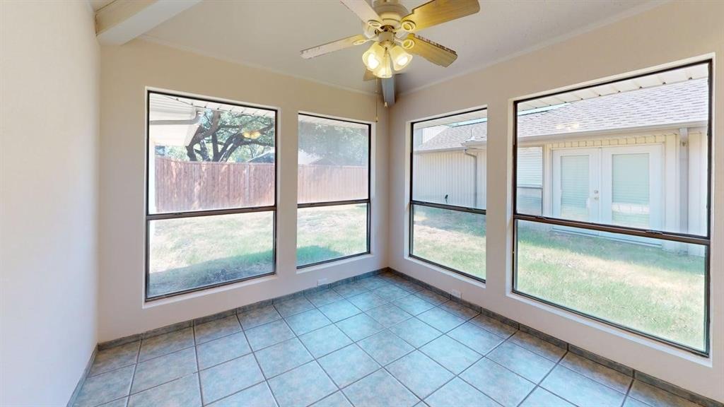 Tile flooring, multiple windows, exposed beam ceiling, and a ceiling fan with integrated lighting