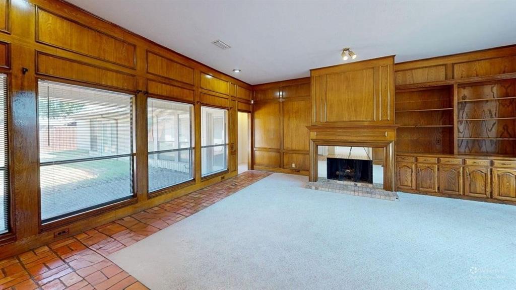 Wood paneling, built-in shelving, built-in cabinetry, brick fireplace, and large windows