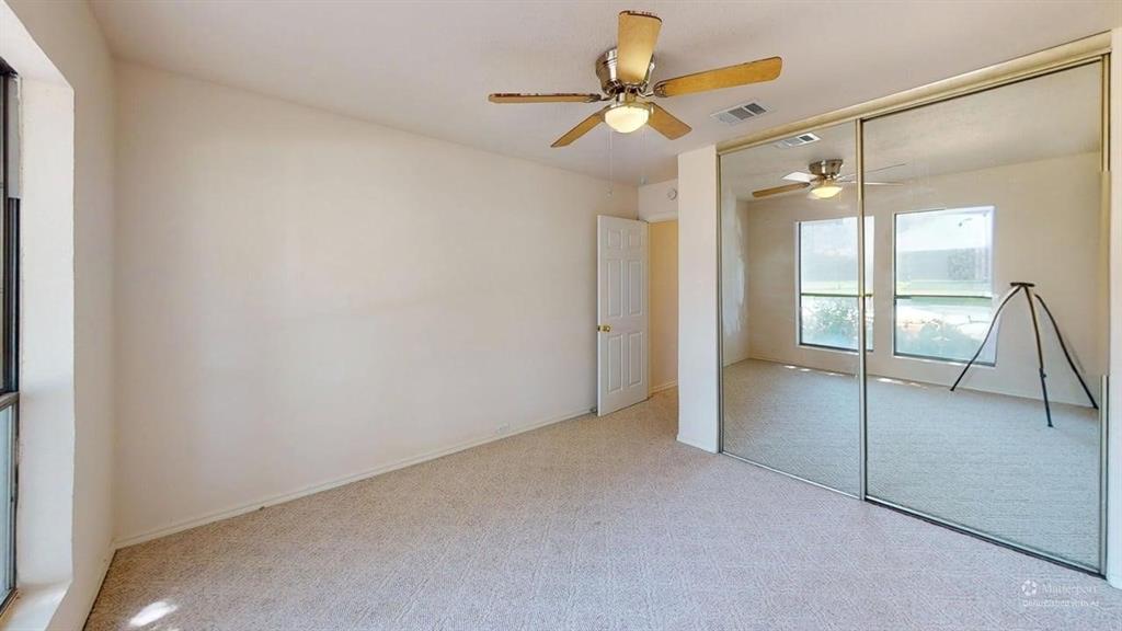 Wall-to-wall carpeting, ceiling fan with integrated lighting, mirrored sliding wardrobe doors, paneled interior door, and large window