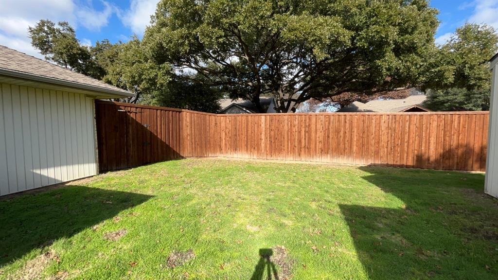 Expansive backyard featuring a stained wood privacy fence and a manicured lawn