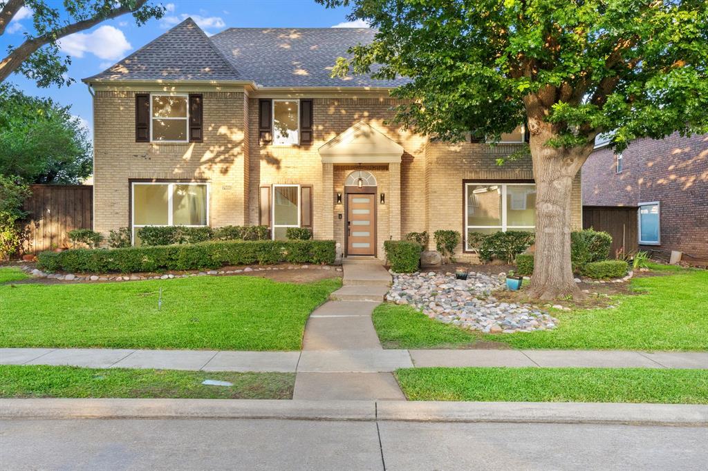 Traditional brick facade residence featuring a prominent entryway, dark-shingle roof, and decorative window shutters