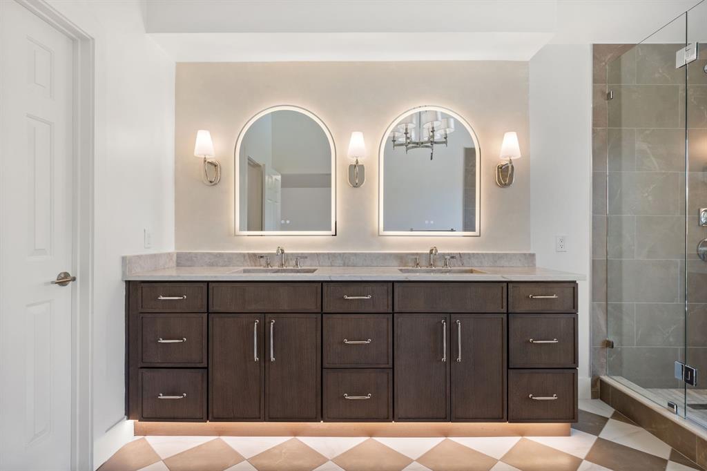 Double vanity with dark wood-finish cabinetry, light stone countertop, and two vessel sinks