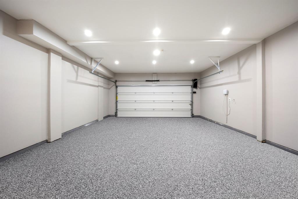 Spacious garage featuring a speckled epoxy floor, recessed ceiling lighting, a panel garage door, and light neutral wall tones
