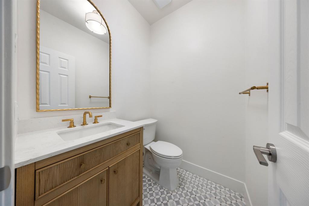 Powder room featuring a wood-finish vanity with a white countertop and integrated rectangular sink