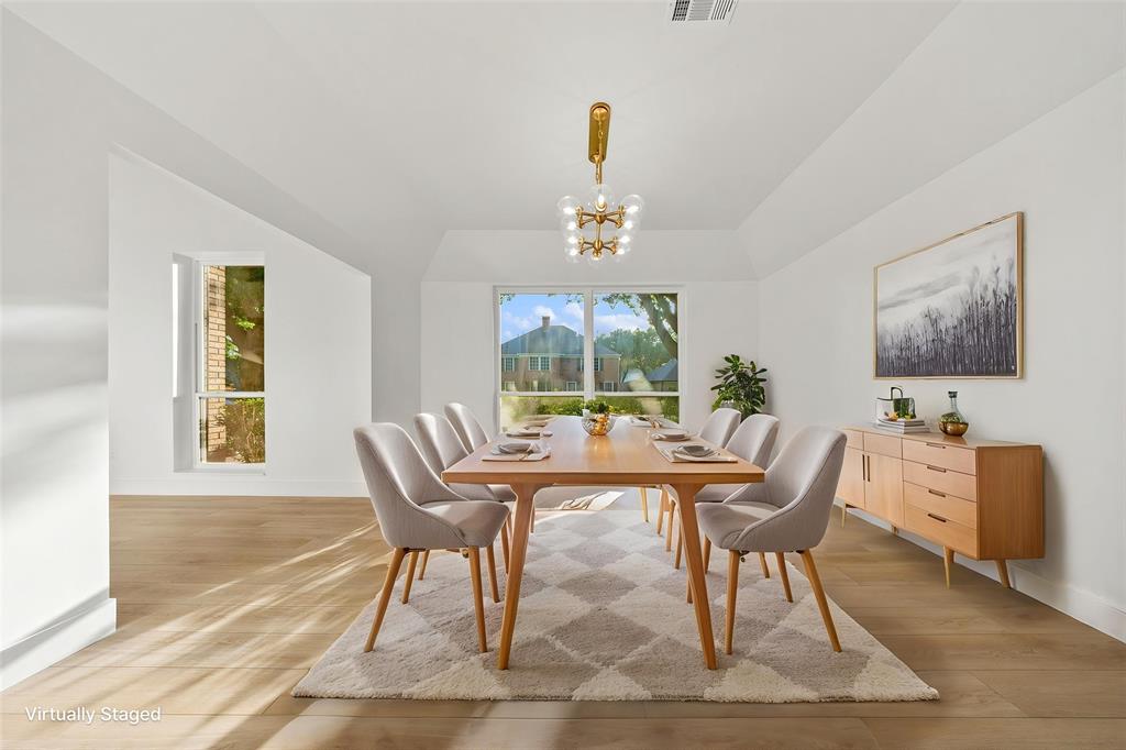 Dining area featuring wood-finish flooring, vaulted ceiling, and a prominent window