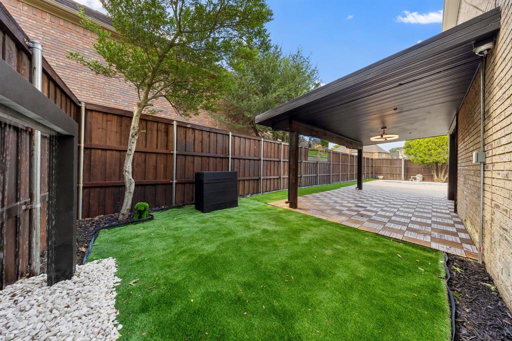 Covered patio featuring patterned tile flooring, wood support columns, and an overhead light fixture
