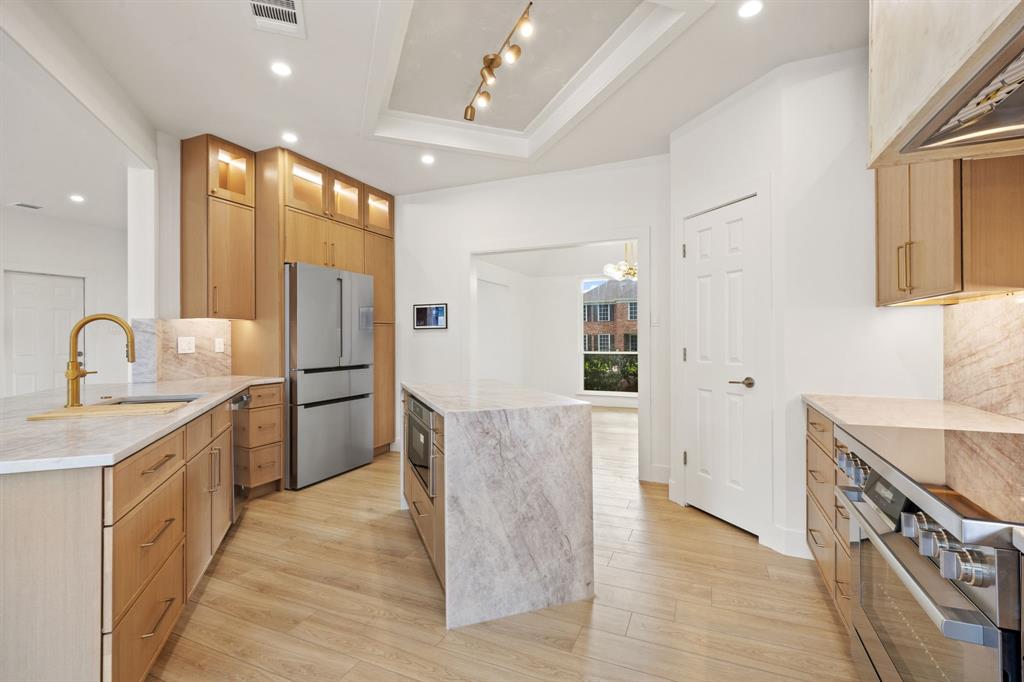 Modern kitchen featuring light wood-finish cabinetry, stainless steel appliances, and light-toned countertops Modern kitchen featuring light wood-finish cabinetry, stainless steel appliances, and light-toned countertops