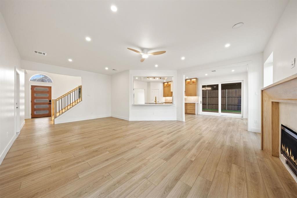 Expansive living area with light wood-finish flooring, recessed lighting, and a modern ceiling fan Expansive living area with light wood-finish flooring, recessed lighting, and a modern ceiling fan