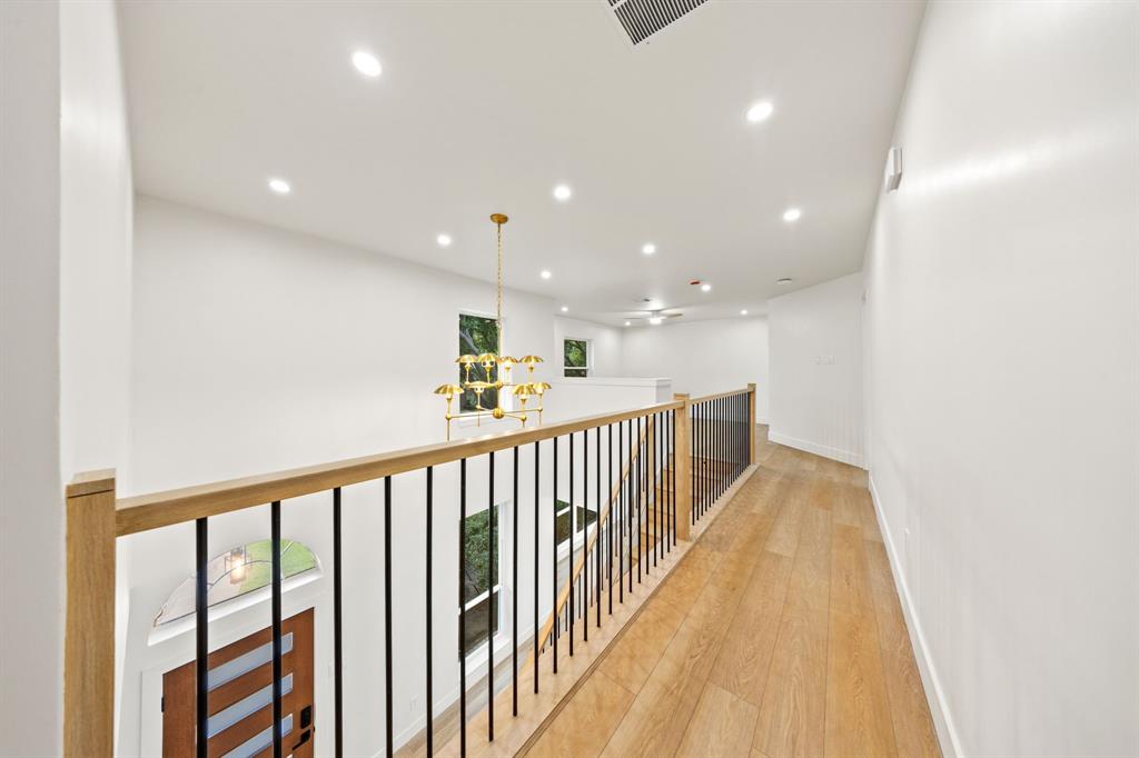 Upper-level hallway with wood-finish flooring, white walls, and recessed lighting