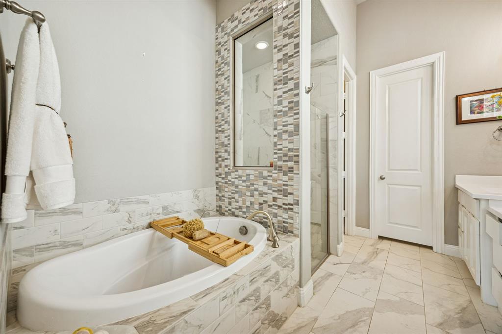 garden tub and separate shower with view of door leading to huge walk-in closet