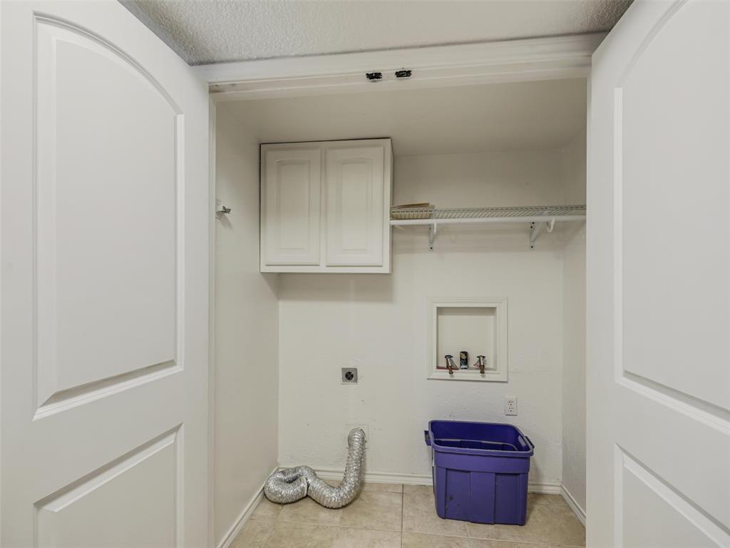 Laundry area with white cabinetry, tile flooring, and integrated shelving