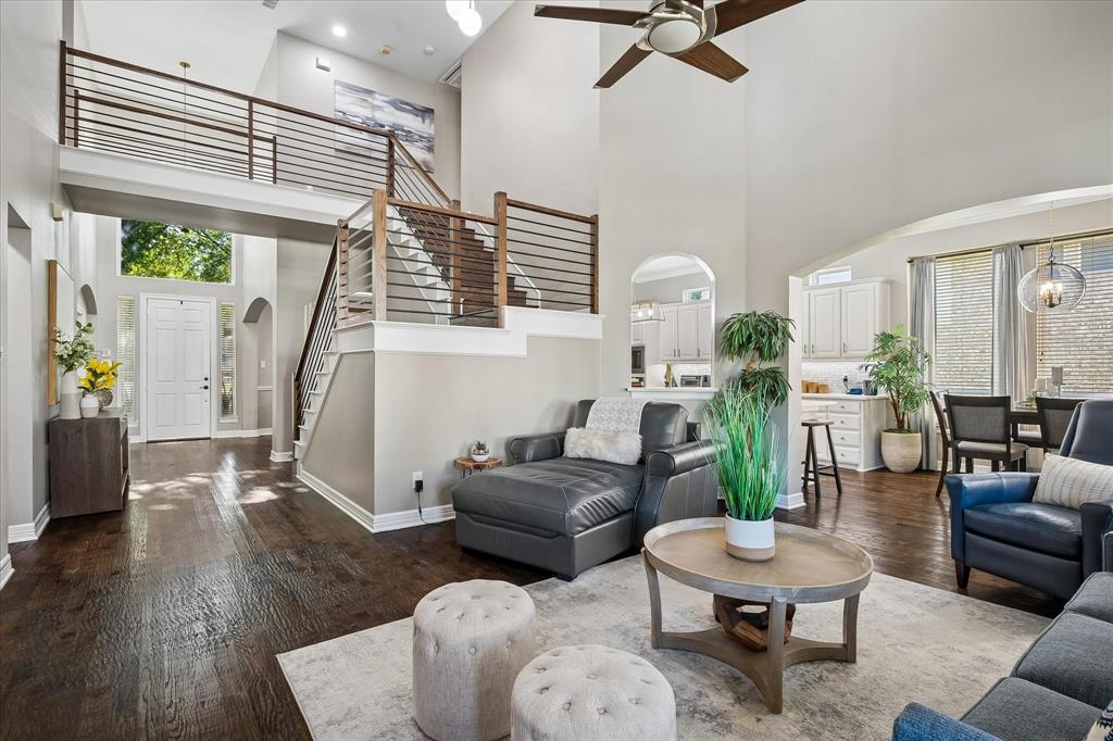 Two-story living area with high ceilings, wood-finish flooring, and a contemporary open-riser staircase with horizontal metal railings