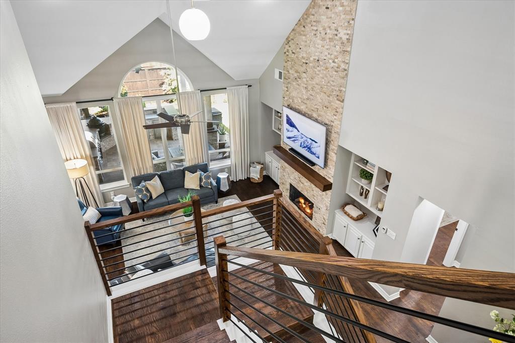 Two-story living area with a stone-clad fireplace, integrated shelving, and large windows