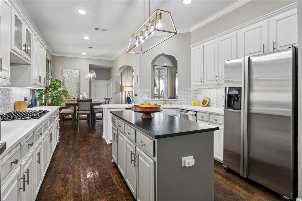 Gourmet kitchen with white cabinetry, dark wood-finish flooring, stainless steel appliances, a center island with a dark countertop, and recessed lighting