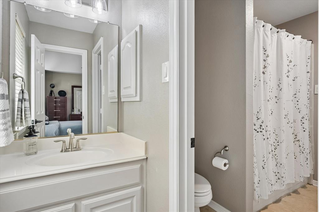 White vanity with integrated sink, brushed nickel faucet, wall-mounted mirror, and overhead lighting