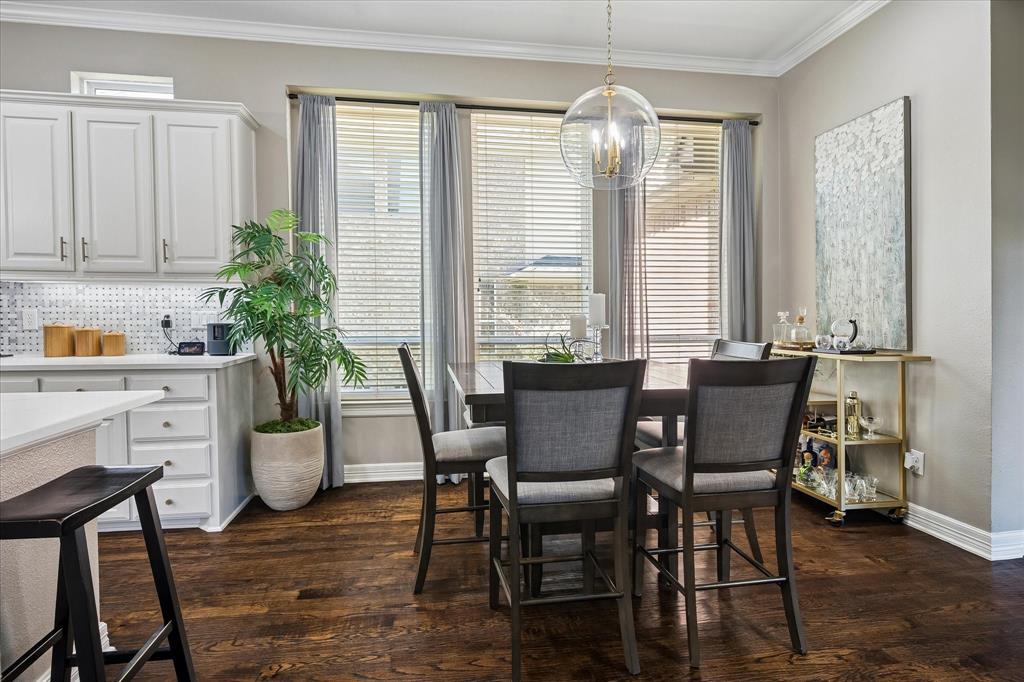 Hardwood flooring, white cabinetry, integrated lighting, large windows with blinds, and a contemporary spherical chandelier
