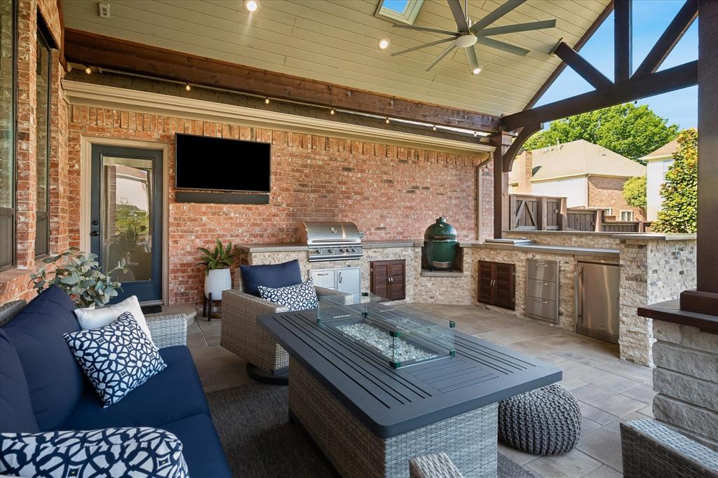 Covered patio featuring a ceiling fan, skylight, built-in outdoor kitchen with stainless steel appliances, and a paver patio surface