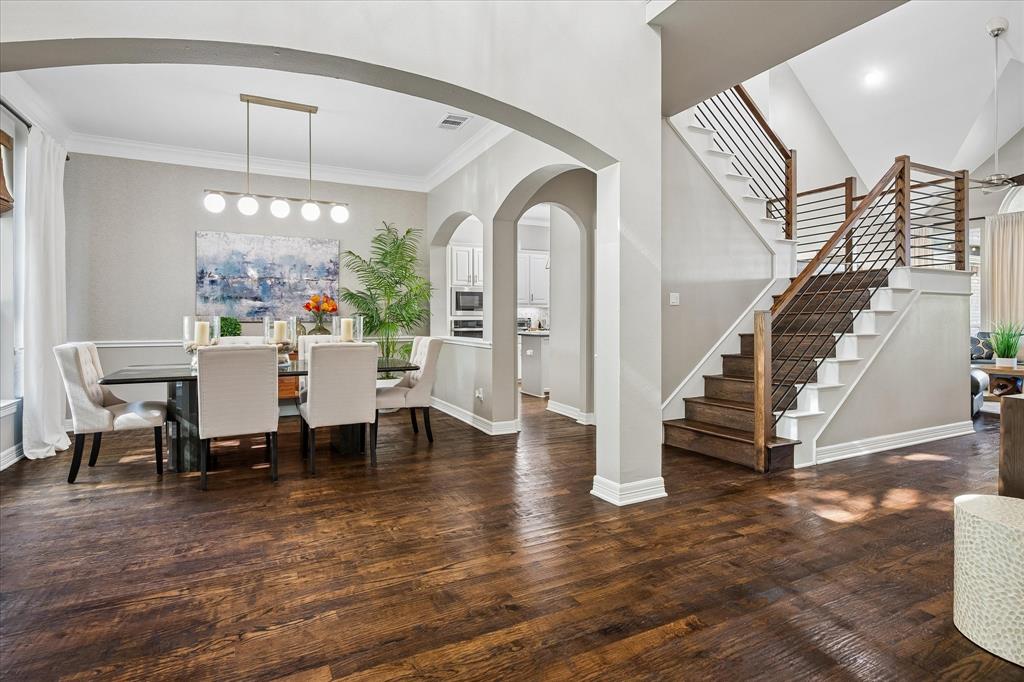 Hardwood flooring throughout, arched doorways, a contemporary staircase with wood and metal railing, recessed lighting, and crown molding