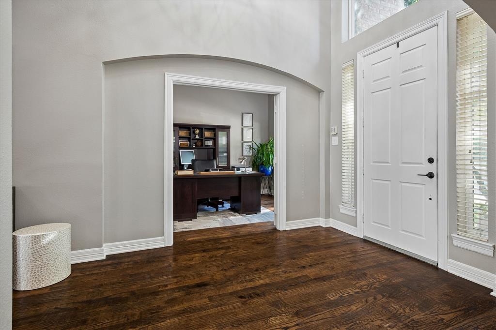 Hardwood flooring, arched doorway, panel-style front door, side-light windows, built-in shelving