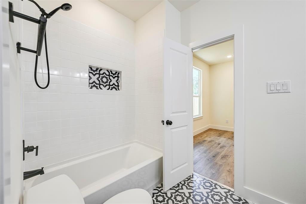 Bathroom featuring a white subway tile surround, patterned tile flooring, and matte black fixtures Bathroom featuring a white subway tile surround, patterned tile flooring, and matte black fixtures