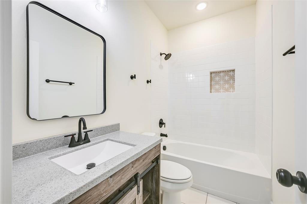 Bathroom featuring a white subway tile shower surround with a decorative niche, a white tub, and matte black fixtures Bathroom featuring a white subway tile shower surround with a decorative niche, a white tub, and matte black fixtures