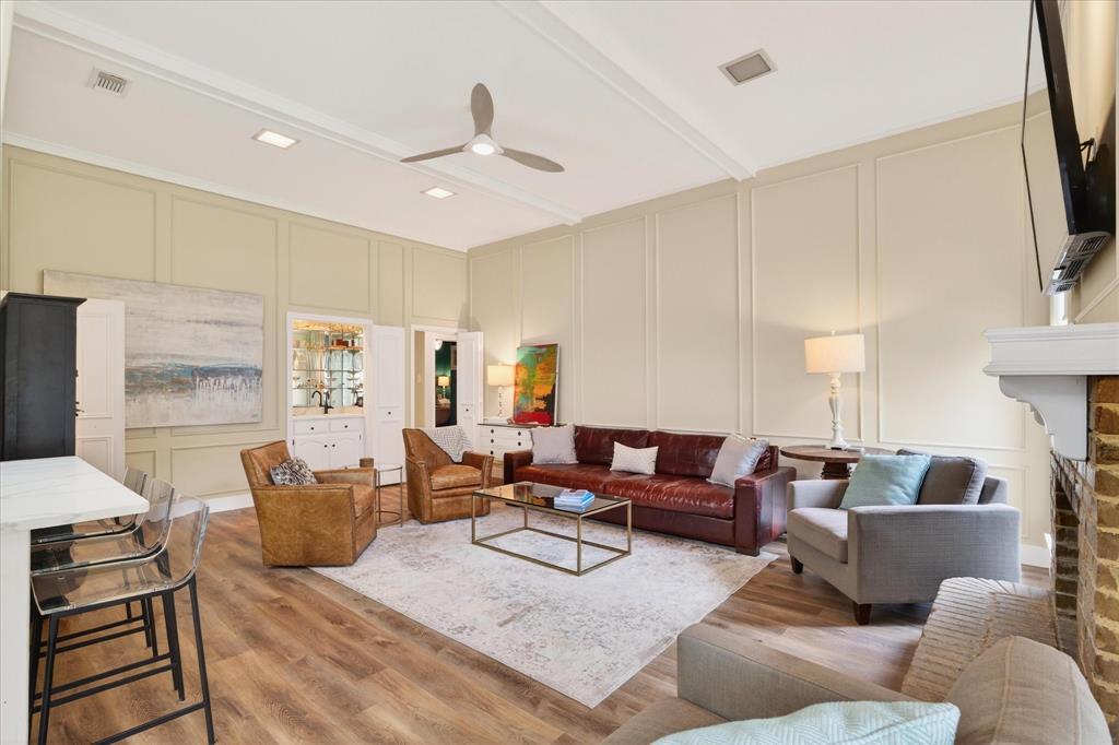 Living area featuring wood-finish flooring, a built-in wet bar with cabinetry, a brick fireplace with a white mantel, and ceiling-mounted lighting