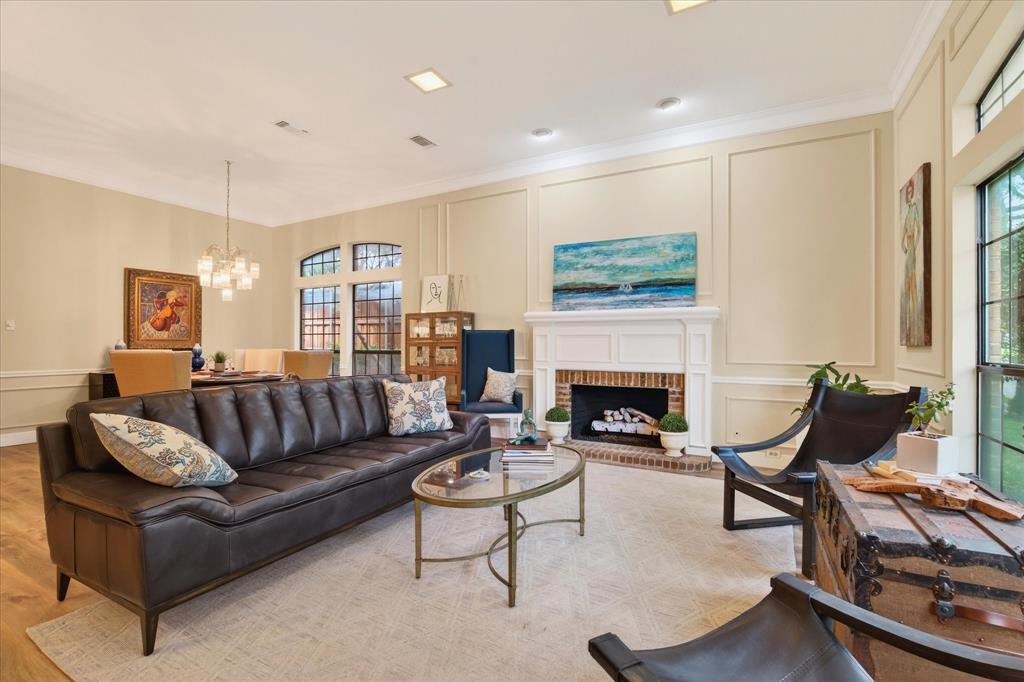 Living area featuring a white mantel fireplace with brick surround, recessed lighting, and wall panel molding