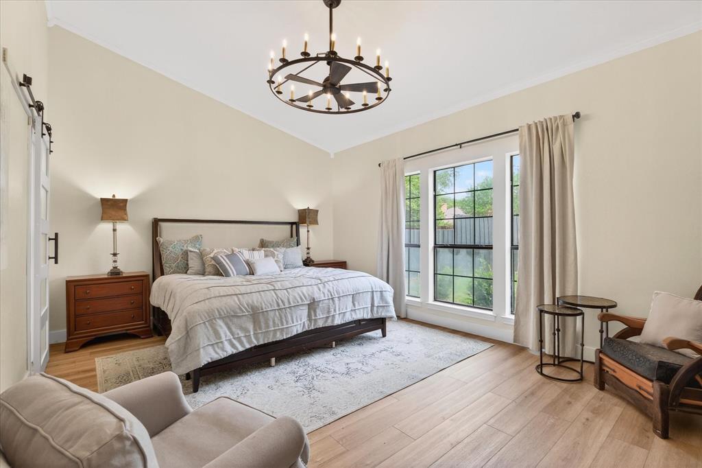 Vaulted ceiling with an iron chandelier, light wood-finish flooring, and a large window with black grilles