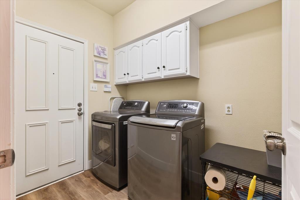 Wood-finish flooring, white paneled door, and upper white cabinetry