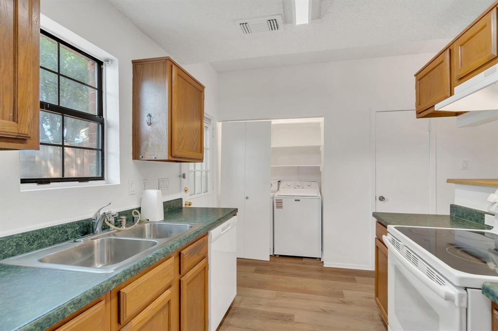Kitchen featuring wood-finish cabinetry, a double basin stainless steel sink, and a built-in electric range