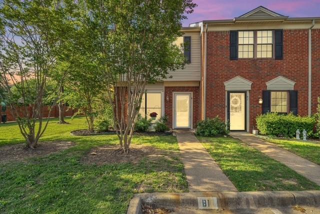 Brick facade with accent siding, individual entryways, mature trees, and a concrete paver walkway Brick facade with accent siding, individual entryways, mature trees, and a concrete paver walkway