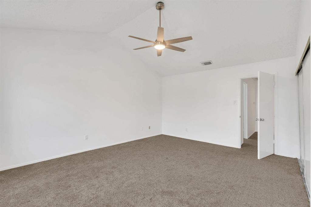 Vaulted ceiling, ceiling fan with integrated lighting, neutral carpet flooring, and white wall finishes
