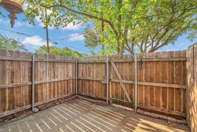 Fenced outdoor area featuring a concrete pad and a wooden gate Fenced outdoor area featuring a concrete pad and a wooden gate
