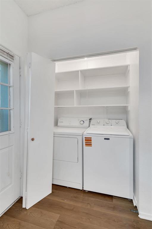 Dedicated laundry area with built-in shelving and wood-finish flooring