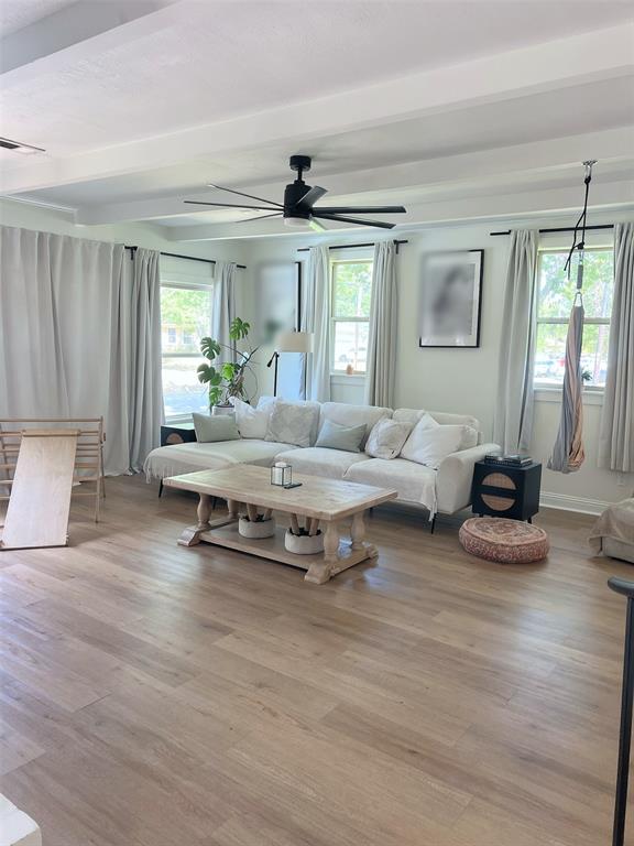 Wood-finish flooring throughout, complemented by a contemporary black ceiling fan and crisp white ceiling beams