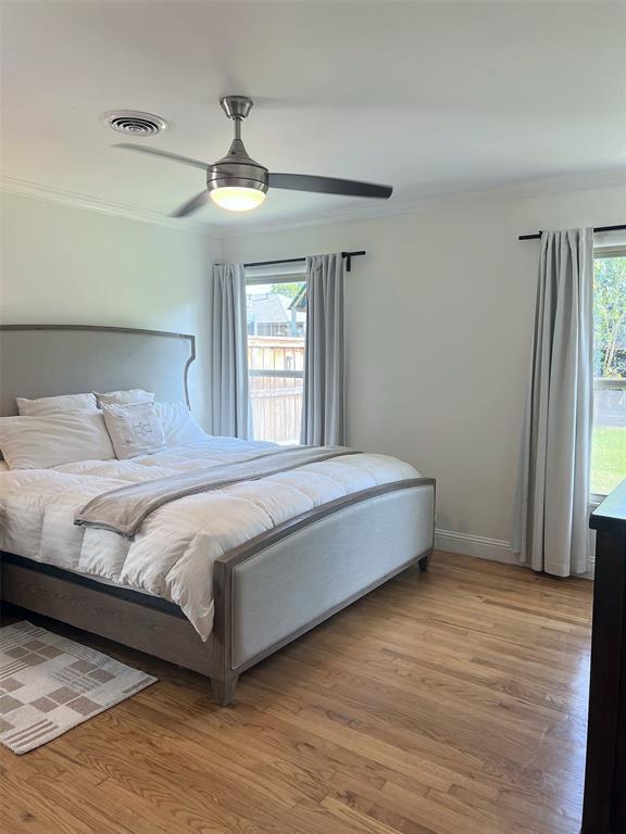 Hardwood flooring, crown molding, dual windows, and ceiling fan with integrated lighting