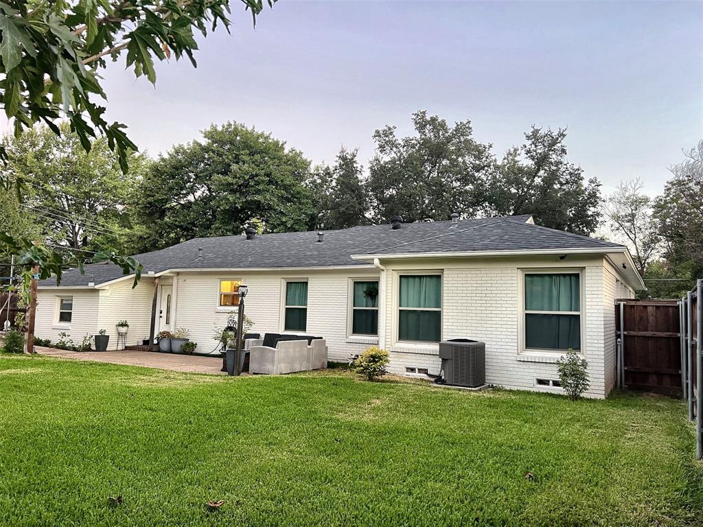 Expansive green lawn with a paver patio and white brick exterior