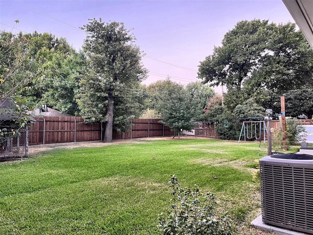 Expansive backyard featuring a lush lawn, mature trees, and privacy fencing