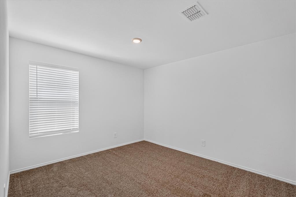 Light-filled room featuring neutral carpeting, white walls, a single window with blinds, and recessed lighting