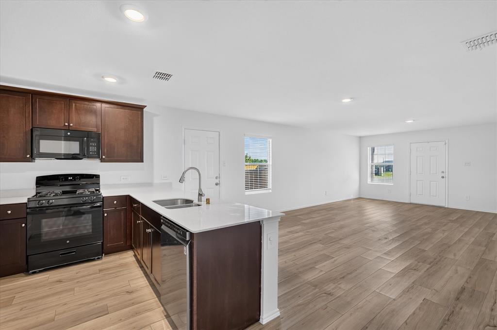 Open-concept living space with wood-finish flooring, recessed lighting, and white walls