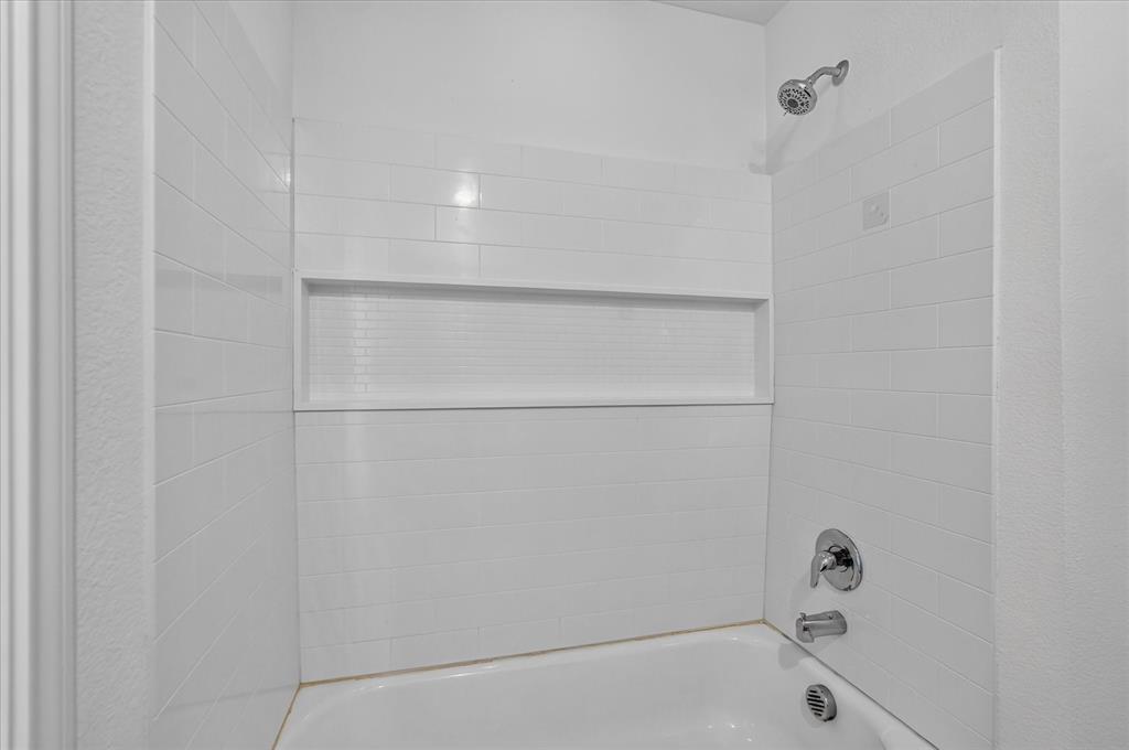 White subway tile shower surround with an integrated niche, chrome fixtures, and a white tub