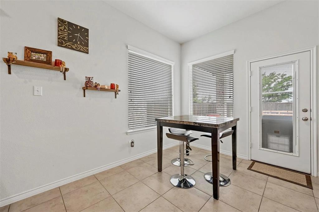 Tile flooring, built-in shelving, multiple windows with blinds, and a glass-paneled exterior door