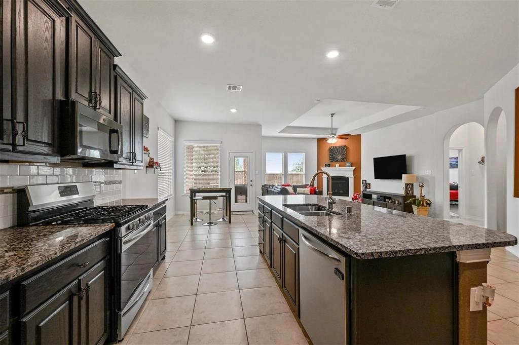 Kitchen features dark wood cabinetry, granite countertops, and stainless steel appliances